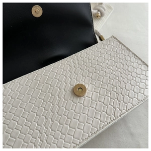 Close-up of white woven texture leather bag with gold magnetic buckle and black lining