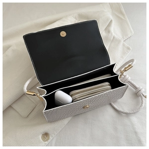 Interior view of white woven shoulder bag showing dual compartments and magnetic clasp