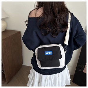 Detail of a black and white nylon crossbody bag worn by a model in a casual setting