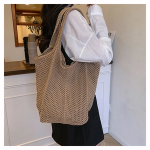 Detailed side view of khaki hollow knit tote bag on shoulder showing large capacity and drape