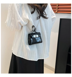 Close-up of black patent leather mini jelly bag with silver clasp and metal chain strap