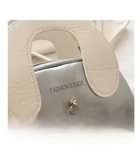Detail of silver metallic shell bag with ivory handles and pearl charm accents