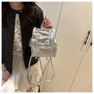Close-up of silver mini backpack with ribbon bows and pleated metallic texture