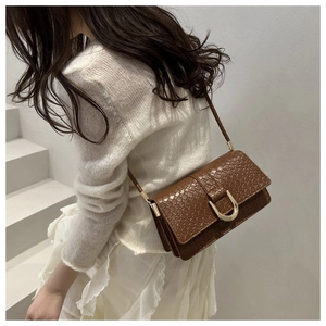 Detail of a brown crocodile texture shoulder bag with a gold U-shaped metal buckle