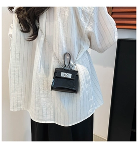 Detalle de un mini bolso jelly negro brillante con cierre giratorio plateado y cadena
