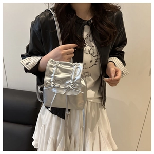Détail d'un mini sac à dos argenté métallisé avec nœuds porté par un mannequin