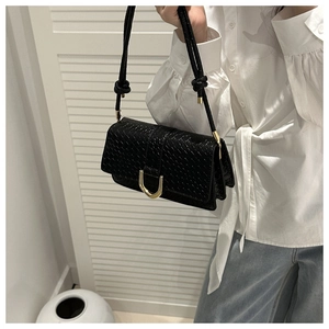 Macro detail of black woven texture shoulder bag with golden buckle and knot shoulder strap