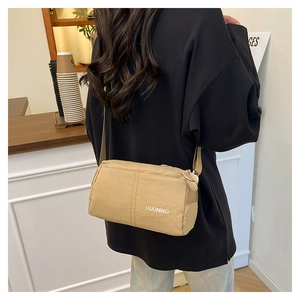 Close-up of khaki nylon crossbody bag with white logo and wide shoulder strap style