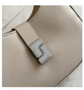 Detail of silver geometric buckle and textured vegan leather on beige hobo saddle bag