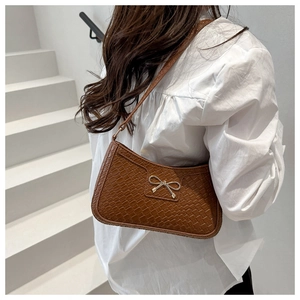 Detail of vintage brown crocodile embossed hobo bag with gold bow clasp worn by model