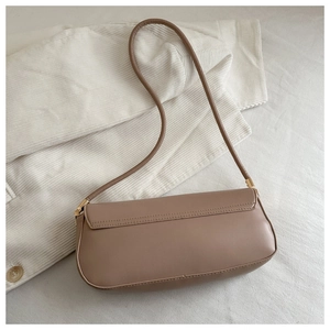 Detail view of khaki leather baguette bag with refined gold hardware on soft fabric