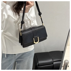 Close-up of black snake pattern texture and gold U-shaped buckle on shoulder bag