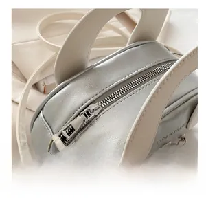 Macro detail of silver shell bag zipper and smooth faux leather texture with printed text