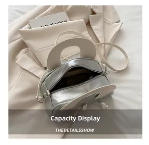 Interior capacity display of silver metallic handbag with cream white straps on soft fabric