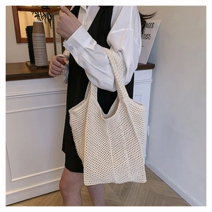 Close-up of cream woven tote bag texture held by model in minimalist indoor setting