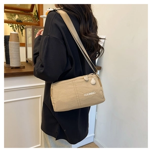 Detailed side view of a beige canvas crossbody bag featuring large circular zipper pulls