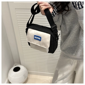 Detail of minimalist black and white crossbody bag with adjustable strap and logo