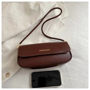 Detail of a brown leather shoulder bag featuring a gold Fashion & Bags logo and slim strap