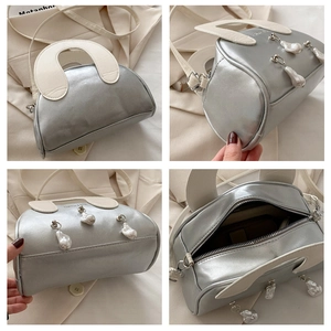 Detail view of silver shell bag showing baroque pearl charms and internal storage space