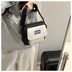 Detail of minimalist black and white crossbody bag with adjustable strap and logo