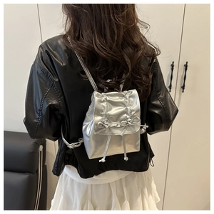 Detail eines silbernen Metallic-Rucksacks mit Schleifen und Kordelzugverschluss