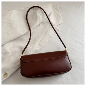 Close-up of the smooth brown faux leather finish and gold buckle of this baguette bag