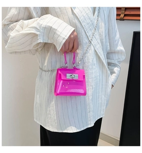Detalle del bolso jelly de PVC rosa intenso con cierre giratorio plateado y correa de cadena