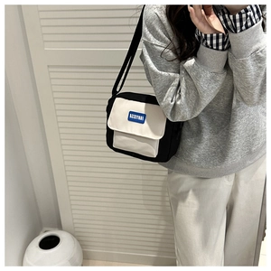 Detailed view of two-tone nylon messenger bag with adjustable strap and logo patch