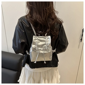 Close-up of a silver bow backpack showing the delicate metallic texture and bow details