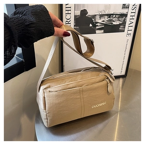 Detail of khaki nylon crossbody bag showing multiple functional zipper compartments