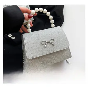 Detail showing the silver glitter texture, large pearl handle, and metal bow on the bag