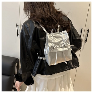 Détail d'un mini sac à dos argenté métallisé avec nœud décoratif et fermeture à cordon