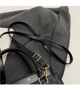Close-up of black leather bag with adjustable shoulder strap and gold metal buckles