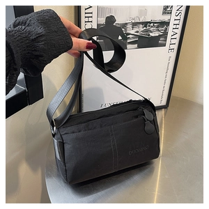 Detail view of the multi-layer black crossbody bag showing durable nylon texture and zippers