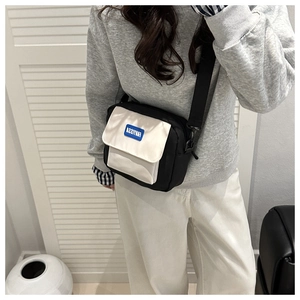 Detail of minimalist black and white crossbody bag with broad shoulder strap on model