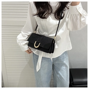 Detail of black woven texture leather bag with elegant golden horseshoe metal buckle