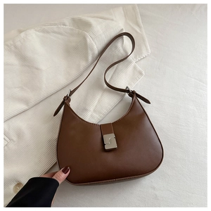 Detail of caramel brown retro shoulder bag with silver geometric lock on white fabric