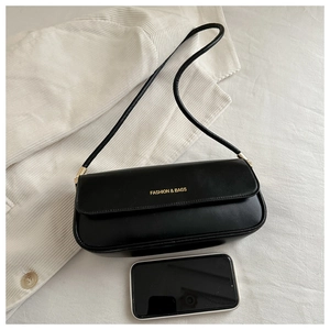 Detail of black leather underarm bag with gold lettering and smartphone for size scale