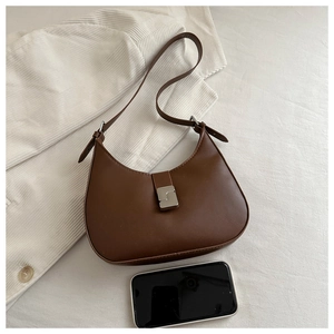 Detail view of brown vintage hobo bag with silver buckle next to a phone for size scale