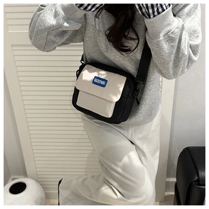 Adjustable black and white crossbody bag with FANYISSA label worn by model