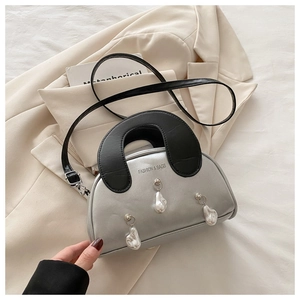 Detail of silver shell bag with contrast handle and elegant dangling pearl accents