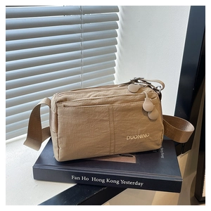 Detail of khaki nylon crossbody bag with multi-zipper compartments and embroidery