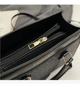 Detailed close-up of smooth gold metal zipper and textured leather on black square bag