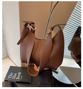 Detail of a brown crescent shoulder bag featuring smooth leather texture and wide strap
