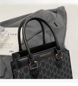 Detail of monogram tote bag with sturdy round handles and gold fashion lettering