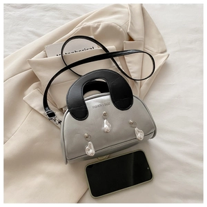 Detail of silver shell bag featuring baroque pearls and black contrast top handles