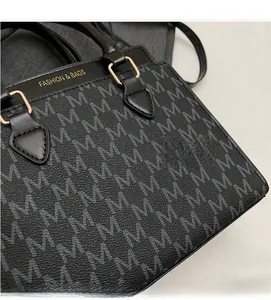 Detailed close-up of black crossbody bag with M-pattern print and gold hardware buckle