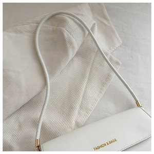 Detail of white leather underarm bag with gold logo and smooth texture finish