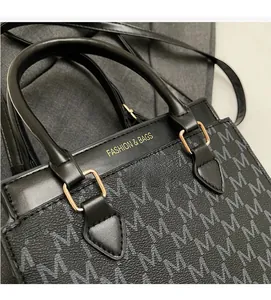 Macro view of monogram printed handbag featuring gold-tone hardware and leather handle