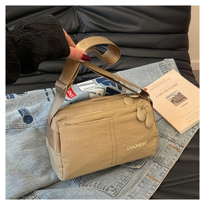 Detail of khaki waterproof nylon crossbody bag with multi-zipper pockets and logo